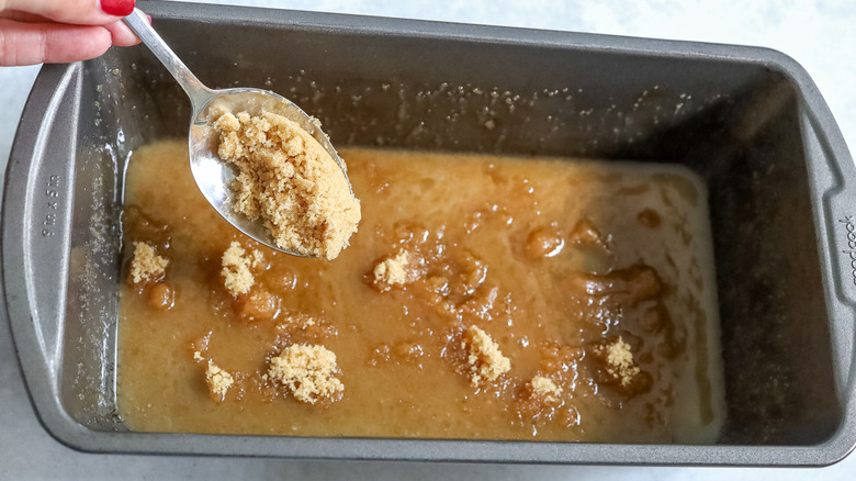 hand spooning sugar into pan