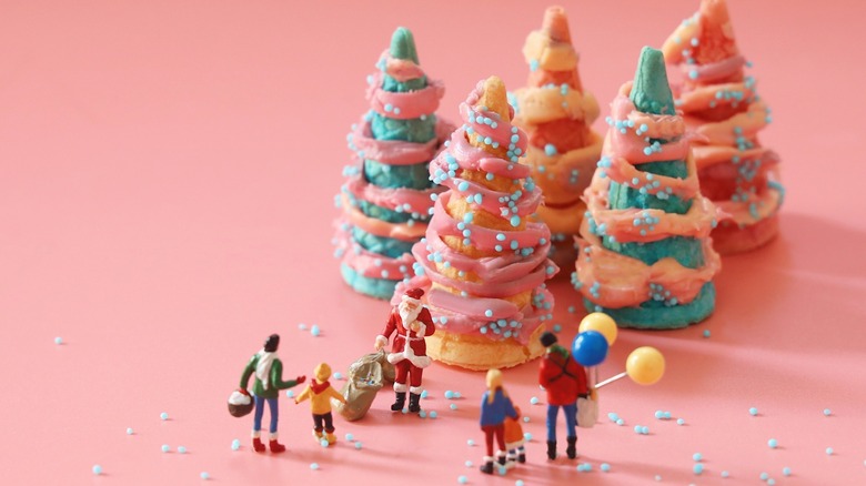 Five Christmas sugar cone trees next to figurines