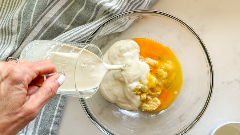 hand adding milk to batter