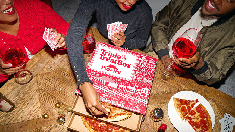 friends playing cards with Pizza Hut wine treat box