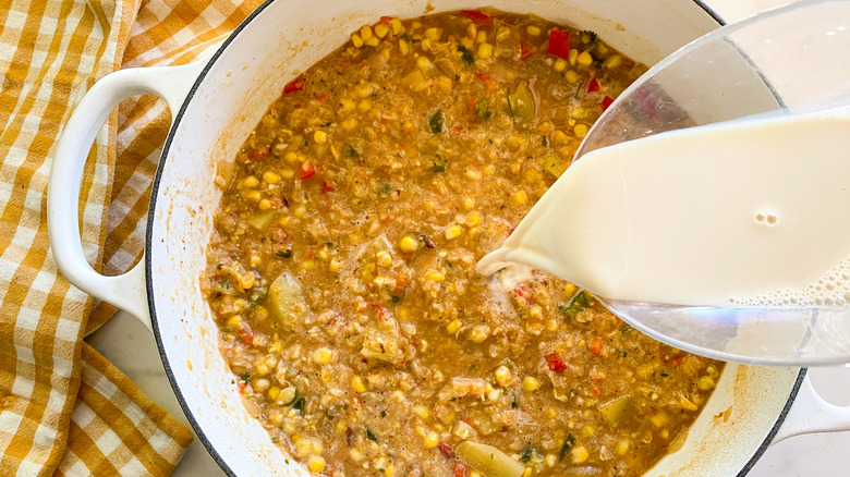 Soy milk pouring into pot of corn chowder