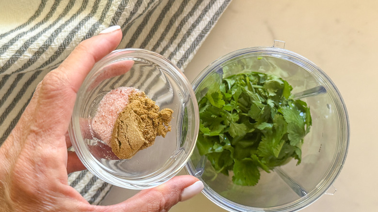 hand adding spices to blender