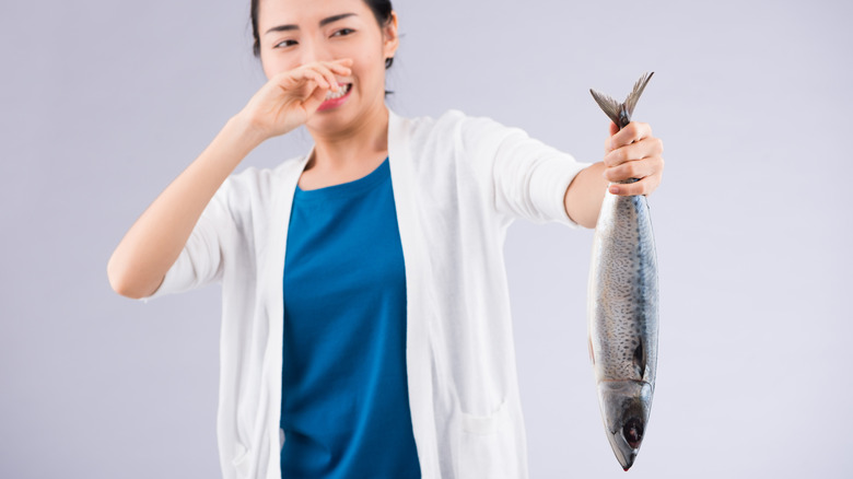 girl holding tuna while covering her nose