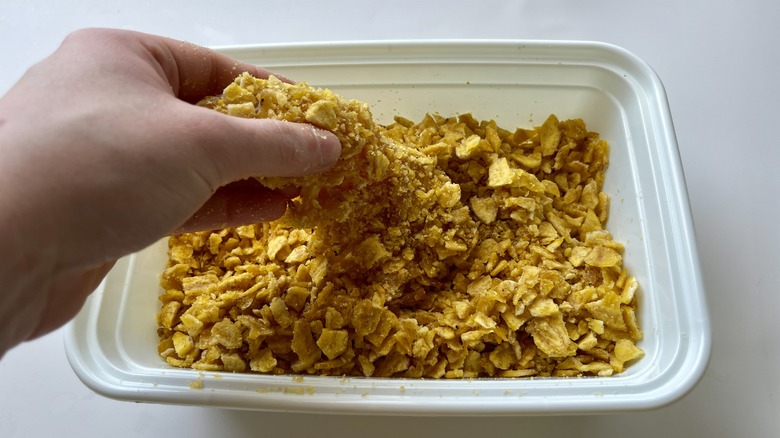 hand dipping chicken in crumbs