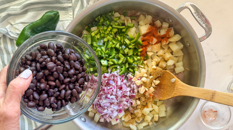 hand adding beans to pan