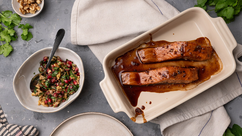 serving pomegranate glazed salmon from dish, salsa in bowl