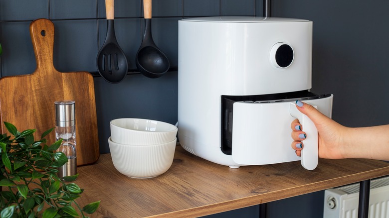 woman pulling air fryer handle