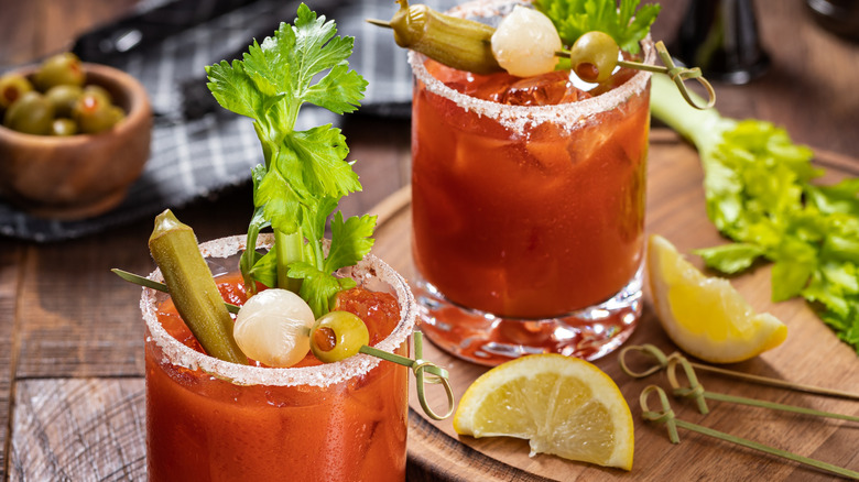 Bloody mary cocktail garnished with celery, okra, onion, olive, and and salt rim