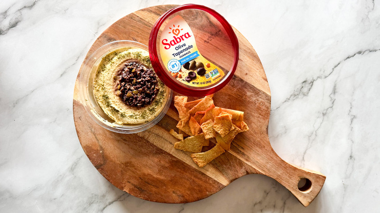 Olive tapanade hummus on marble background with chips