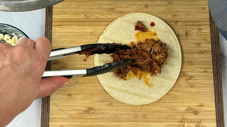 hand putting pork on tortilla