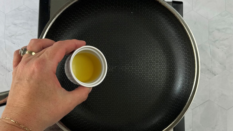 hand pouring oil in pan