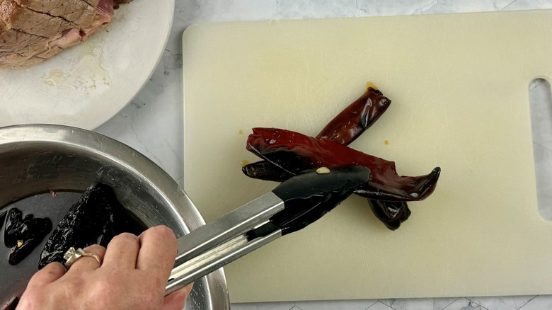 hand holding peppers in tongs