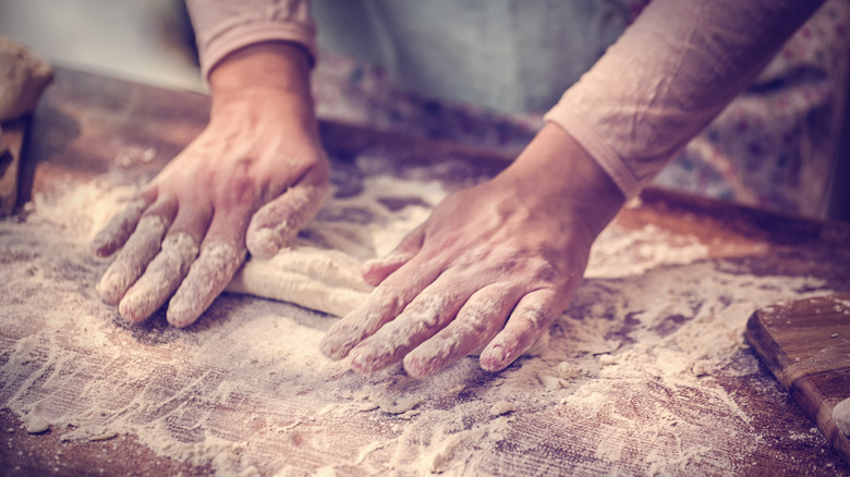 Person rolling dough with hands