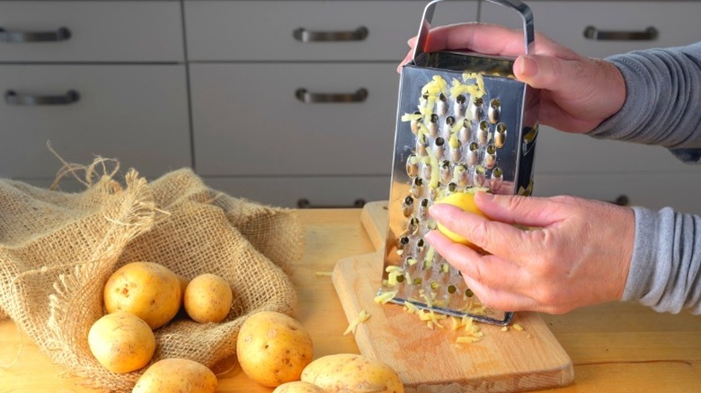 A person grating potatoes