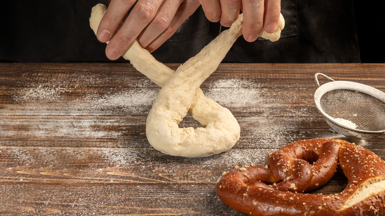 Hands twisting pretzel dough