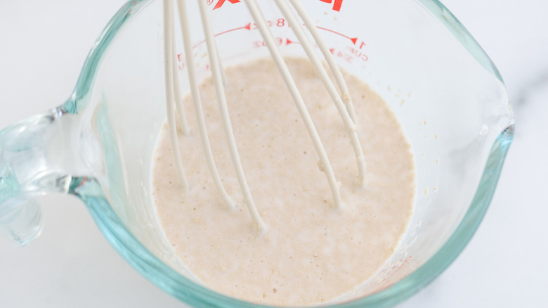 whisk and liquid in measuring cup