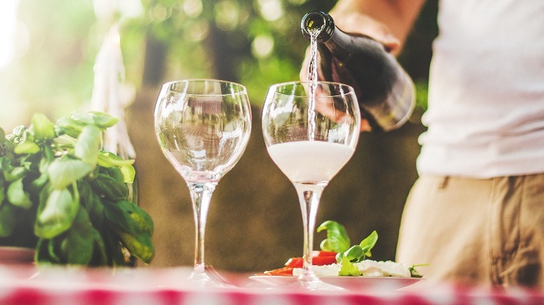 Person pouring Prosecco into two glasses