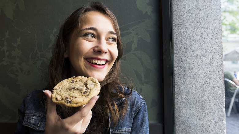 woman eating giant chocolate chip cookie