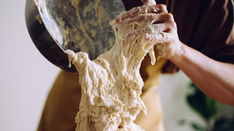 person tilting bread dough from a bowl