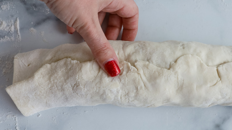 hand holding rolled pastry closed