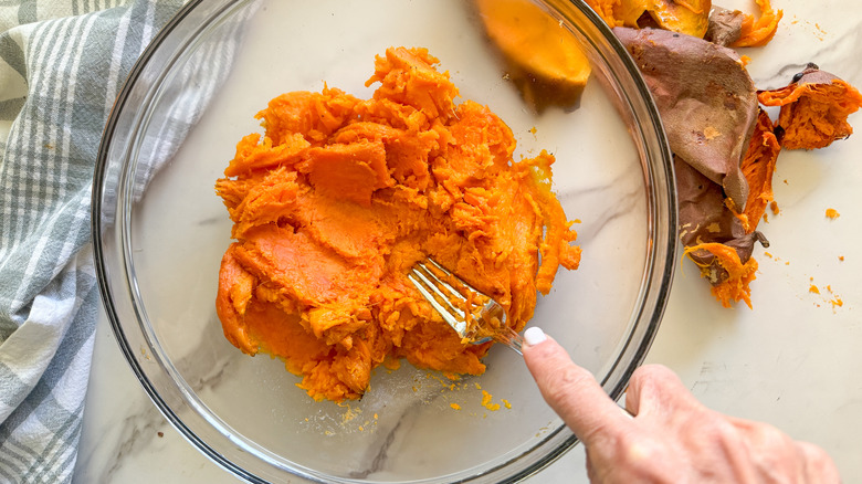 hand mashing sweet potato