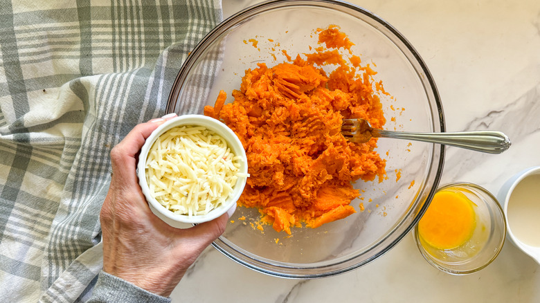 hand adding cheese to bowl