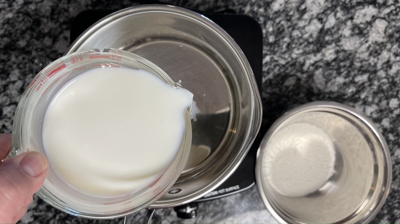 hand pouring milk into pot