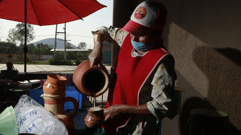 pouring pulque from traditional vat