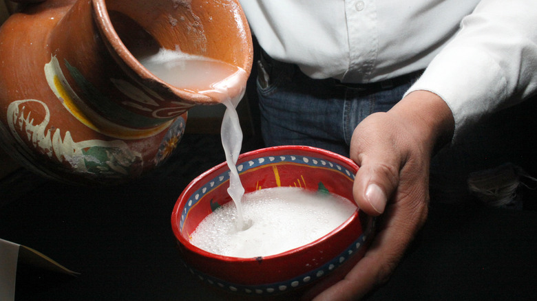 serving pulque into traditional bowl