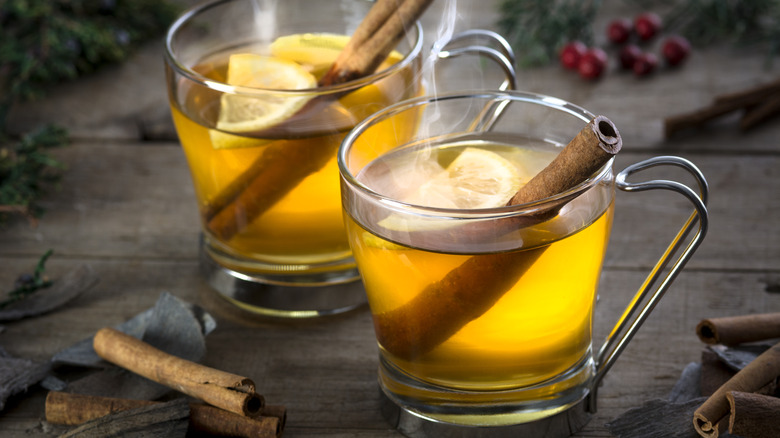 2 glass mugs with hot toddy, lemon slices, cinnamon sticks