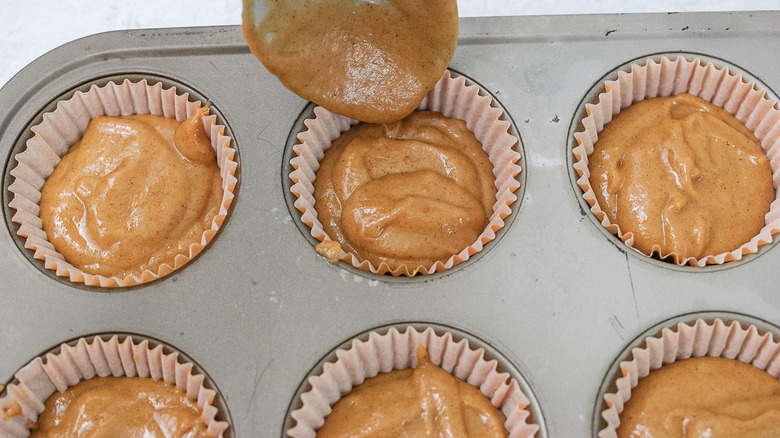 spooning pumpkin cake batter in pan