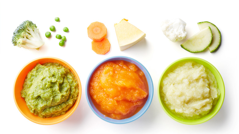 Different vegetable purées in separate bowls on a white background