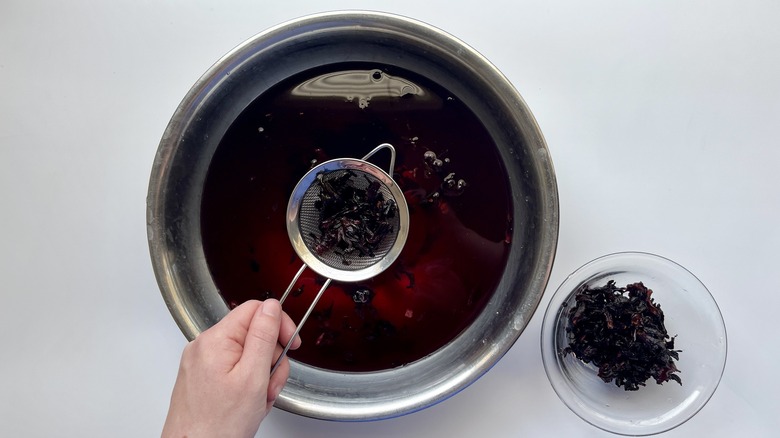 draining hibiscus petals in sieve