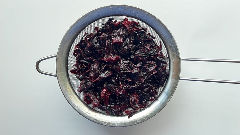 cooked hibiscus petals in sieve