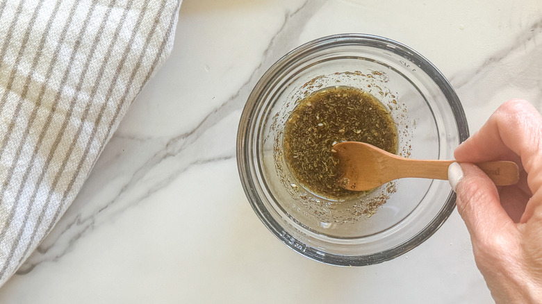 Hand stirring oil and za'atar spice with small wooden spoon