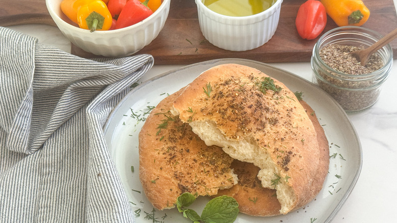 Cut maneesh bread on a white plate next to jar of za'atar