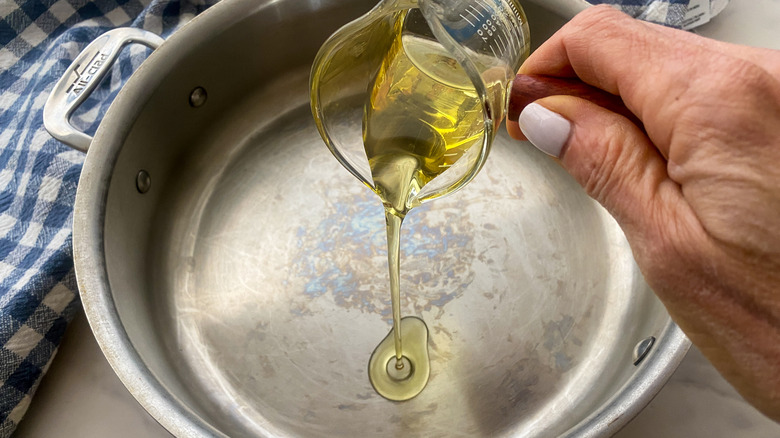 hand adding oil to a pan