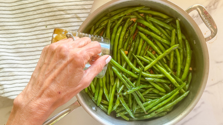 hand adding sauce to pan