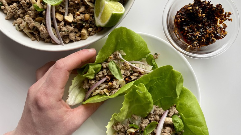 Hand holding chicken-filled lettuce cup