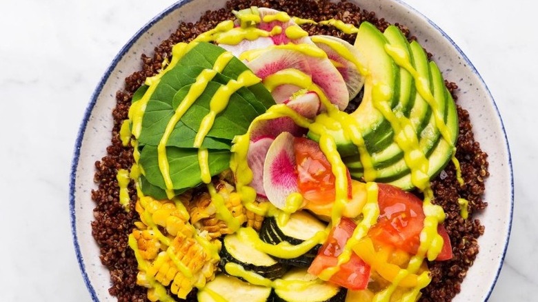 colorful vegetables arranged over red quinoa