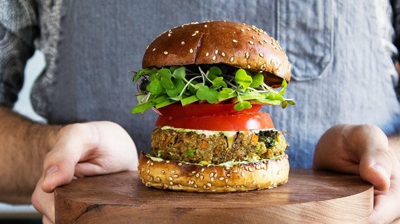Veggie burger topped with red tomatoes and green sprouts