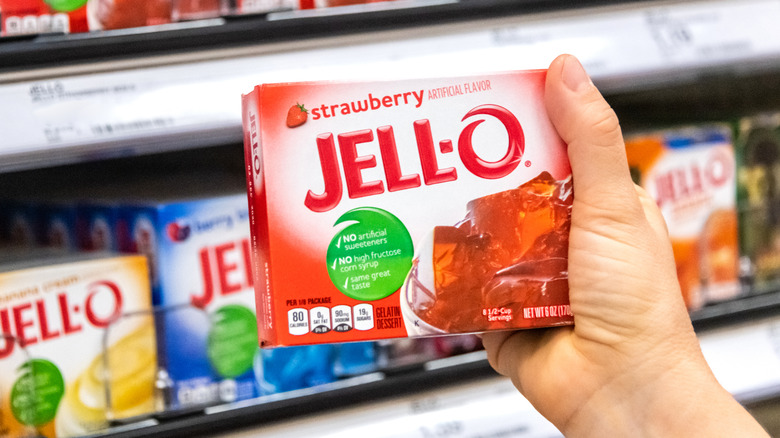 holding Strawberry jello box in aisle