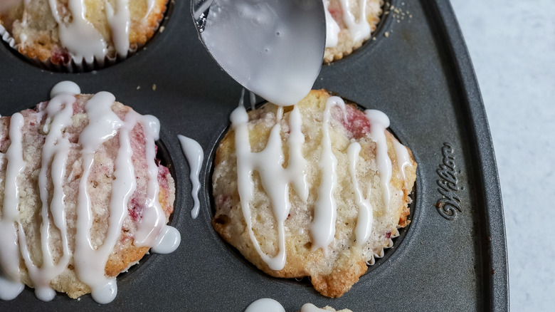 glaze being drizzled over muffins