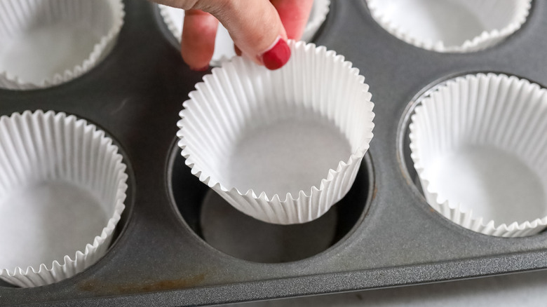 a muffin pan being lined