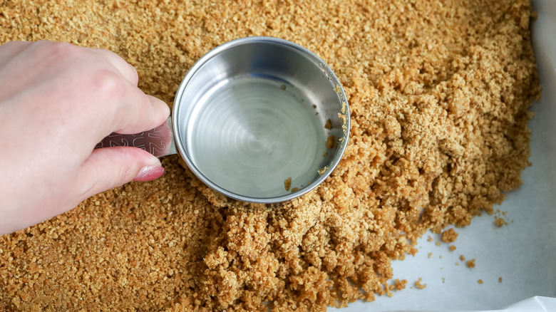 graham cracker crust being pressed into pan