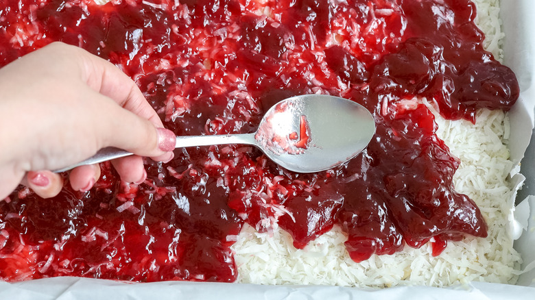 raspberry jam being spread over coconut