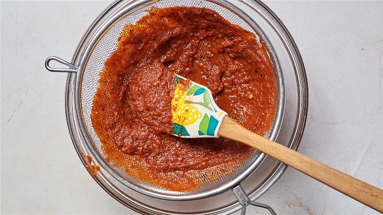 straining chile sauce in mesh strainer