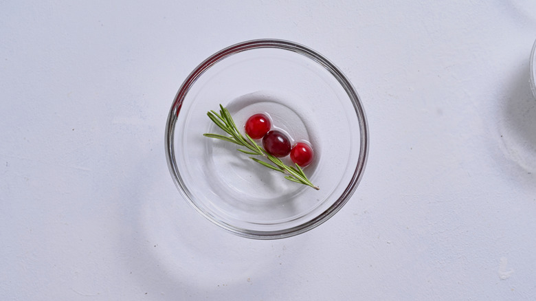 cranberries and rosemary in bowl of syrup