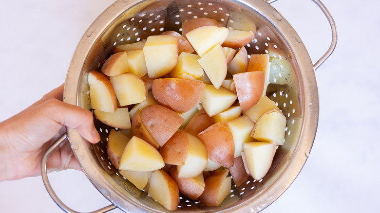 hand holding potatoes in colander