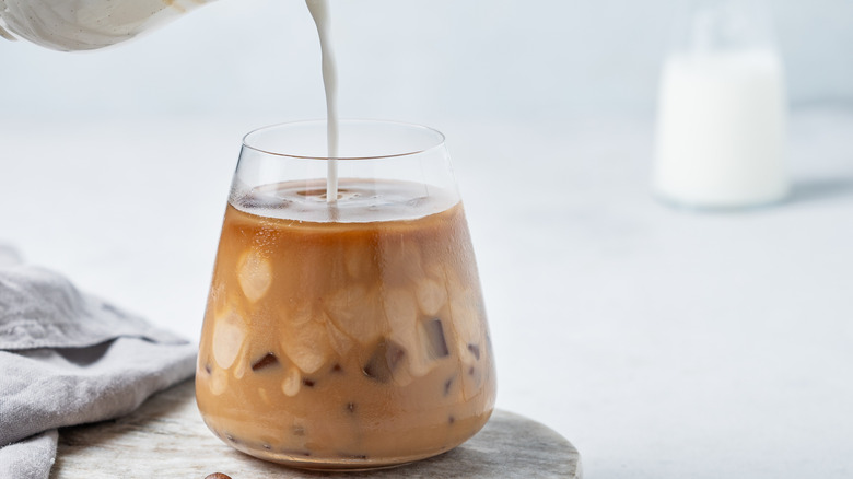 Milk being poured into an iced coffee
